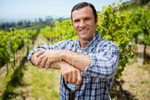 Portrait of vintner standing with shovel in vineyard