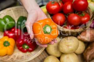 Woman holding fresh bell pepper at vegetable stall