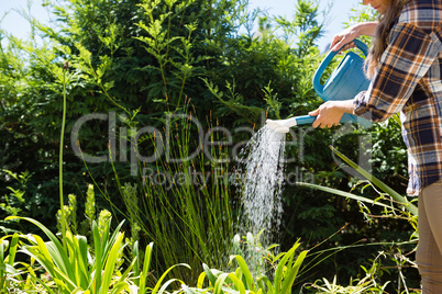 Woman watering plants with watering can in garden