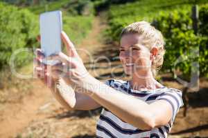 Happy woman talking selfie with mobile phone in vineyard