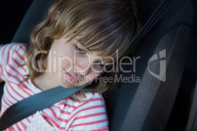 Teenage girl sitting in the back seat of car