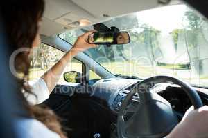 Woman looking into rear view mirror while driving a car