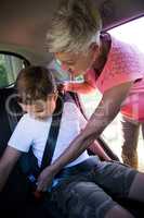 Grandmother securing her grandson with seat belt