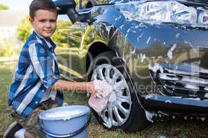 Teenage boy washing a car on a sunny day