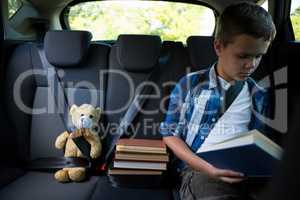 Teenage boy reading book in the car