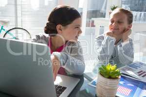 Kids as business executives discussing over laptop