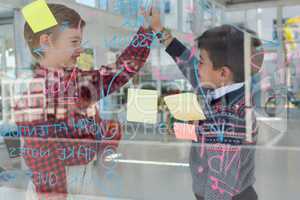 Kids as business executives giving high five to each other near whiteboard