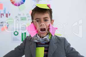 Boy as business executive with sticky notes on his face
