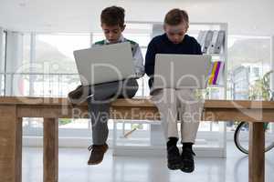 Kids as business executives using laptop while sitting on table