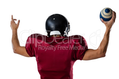 Rear view of player holding football with arms raised