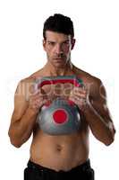 Portrait of shirtless sportsman exercising with kettle bell