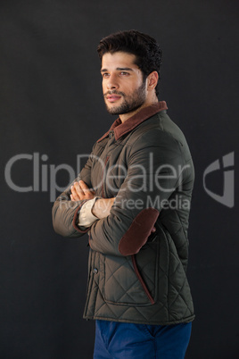 Man standing with arm crossed against black background