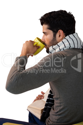 Thoughtful man having a mug of coffee while reading book