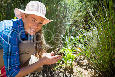 Portrait of happy woman planting sapling in garden