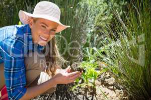 Portrait of happy woman planting sapling in garden
