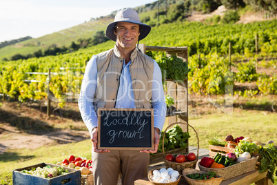 Portrait of happy man standing with slate at vegetable stall