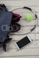 High angle view of gray bag on sports shoes with tennis gear by mobile phone and sunglasses