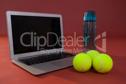 Close up of fluorescent yellow tennis balls by laptop and water bottle