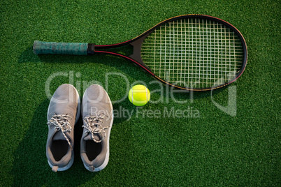 Overhead view of racket with tennis ball and sports shoes