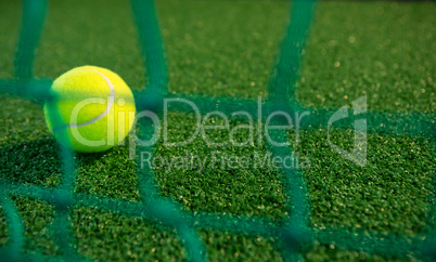 Close up of tennis ball seen through net