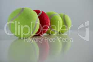 Red and fluorescent tennis ball arranged in row