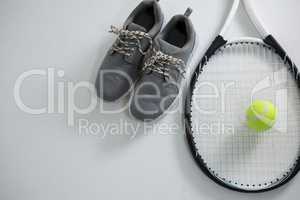 Close up of racket with tennis ball by sports shoe