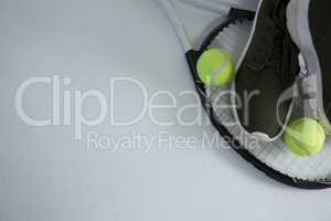 Cropped image of sports shoe with balls on racket
