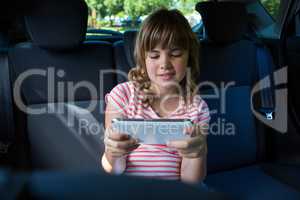 Teenage girl using digital tablet in the back seat of car