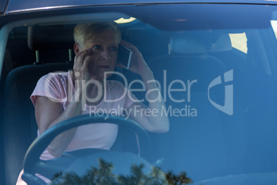 Senior woman talking on mobile phone in car