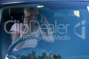 Senior woman talking on mobile phone in car