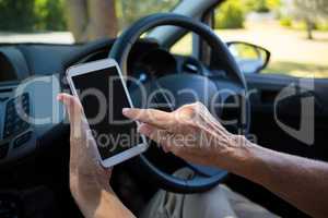 Senior woman using digital tablet while driving car