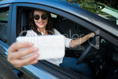 Woman taking selfie with mobile phone in car