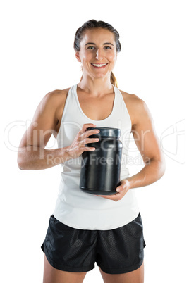 Portrait of smiling female athlete holding supplement jar