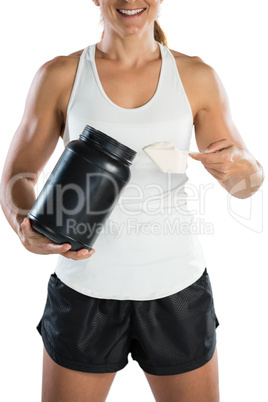 Mid section of smiling female athlete taking supplement powder