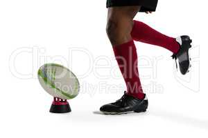 Low section of sportsman kicking rugby ball on tee