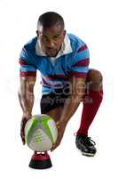 Full length portrait of male rugby player keeping ball on tee