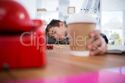 Boy as business executive sleeping while holding coffee cup