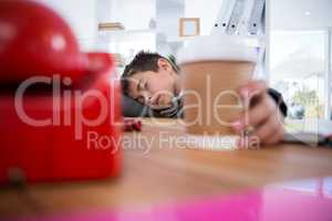 Boy as business executive sleeping while holding coffee cup