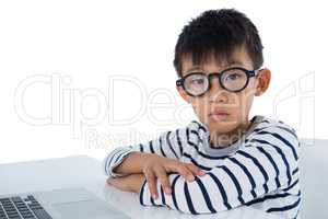 Boy sitting with laptop against white background