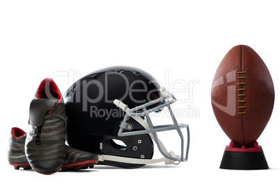Close up of sports shoes and helmet by American football on tee