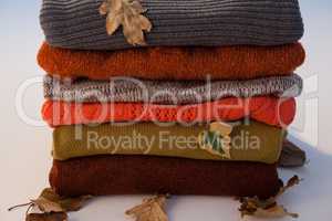 Stack of woolen clothing with autumn leaves