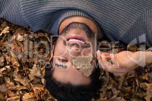 Overhead of man lying on autumn leaves