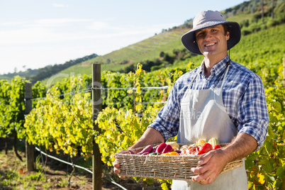 Portrait of happy man holding a basket of fresh vegetables