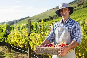 Portrait of happy man holding a basket of fresh vegetables