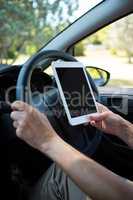 Senior woman using digital tablet while driving a car