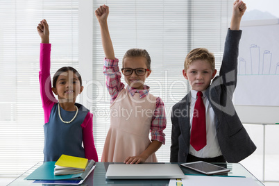 Kids as business executive smiling with their hands raised in the office