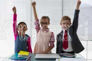 Kids as business executive smiling with their hands raised in the office