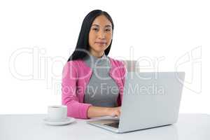 Female executive using laptop against white background