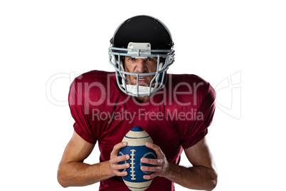 Portrait of aggressive American football player wearing helmet holding ball