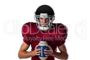 Portrait of aggressive American football player wearing helmet holding ball